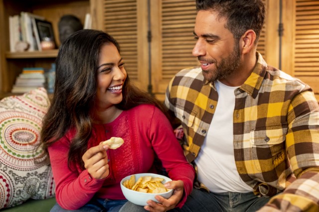 Couple Snacking On Ritz Chips on a Couch